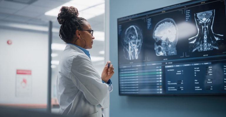 Medical Science Hospital: Confident Black Female Neurologist, Neuroscientist, Neurosurgeon, Looks at TV Screen with MRI Scan with Brain Images, Thinks about Sick Patient Treatment Method. Saving Lives