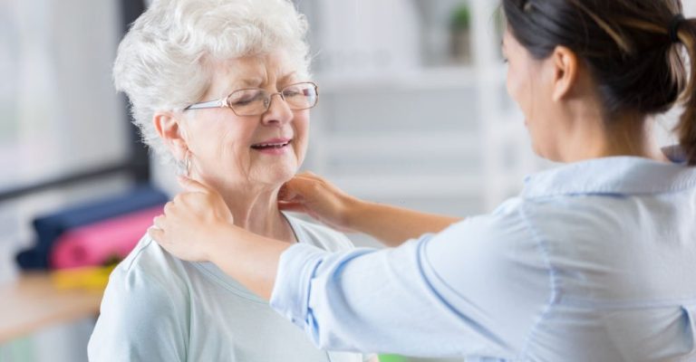 Female chiropractor works on senior woman's neck. The senior woman has a relieved expression on her face.